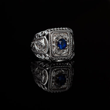 18k white gold men's signet ring with a 0.80ct natural blue sapphire and diamond accents, featuring an ornate medieval design.